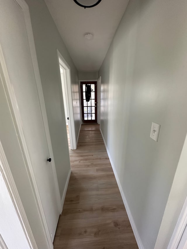 hall with baseboards and light wood-style floors