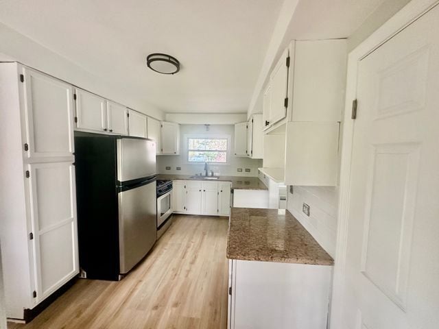 4120 Lotus Dr, Waterford, MI 48329 - kitchen with freestanding refrigerator, range, light wood finished floors, white cabinetry, and stone countertops