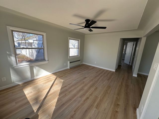 4120 Lotus Dr, Waterford, MI 48329 - empty room with baseboard heating, a ceiling fan, and wood finished floors