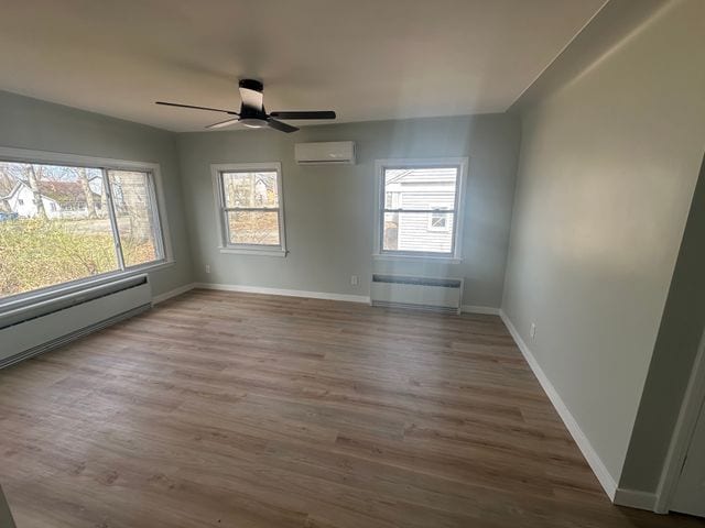 4120 Lotus Dr, Waterford, MI 48329 - empty room featuring an AC wall unit, plenty of natural light, wood finished floors, and a ceiling fan