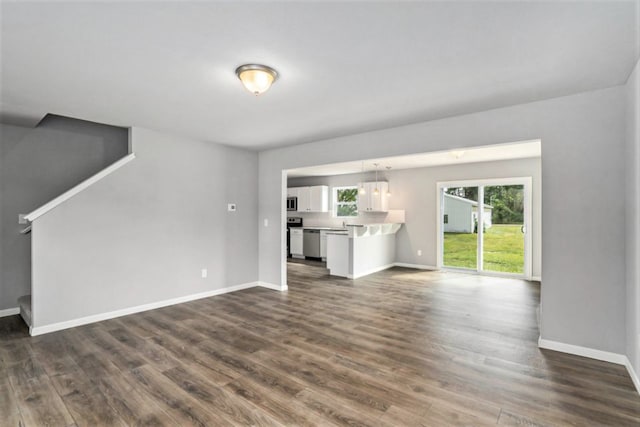 unfurnished living room with dark wood finished floors, stairway, and baseboards