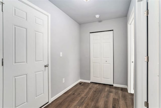 unfurnished bedroom with dark wood-style floors, baseboards, and a closet