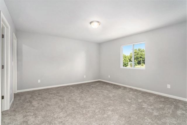 unfurnished room featuring carpet and baseboards