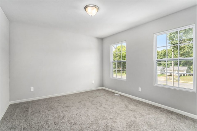 carpeted spare room with visible vents and baseboards