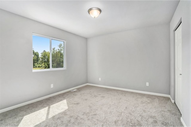 carpeted empty room featuring baseboards