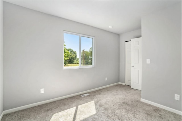 spare room featuring carpet flooring, baseboards, and visible vents