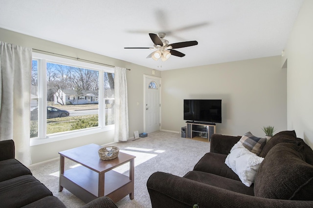 living area featuring carpet, baseboards, and ceiling fan