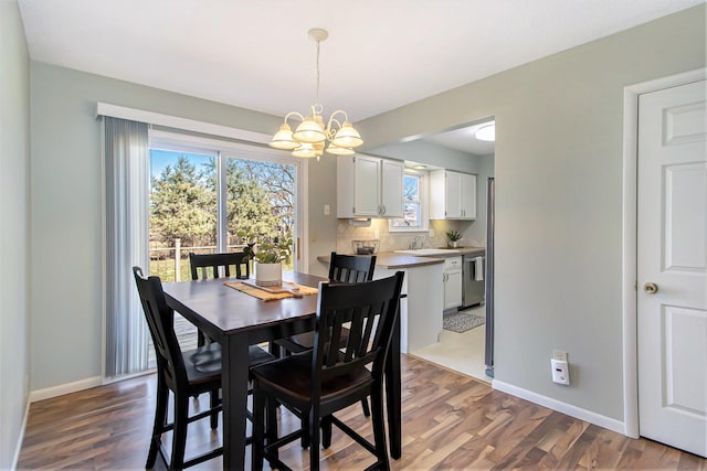 dining room featuring a notable chandelier, wood finished floors, and baseboards