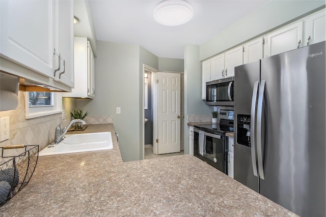 kitchen with a sink, decorative backsplash, light countertops, white cabinets, and stainless steel appliances