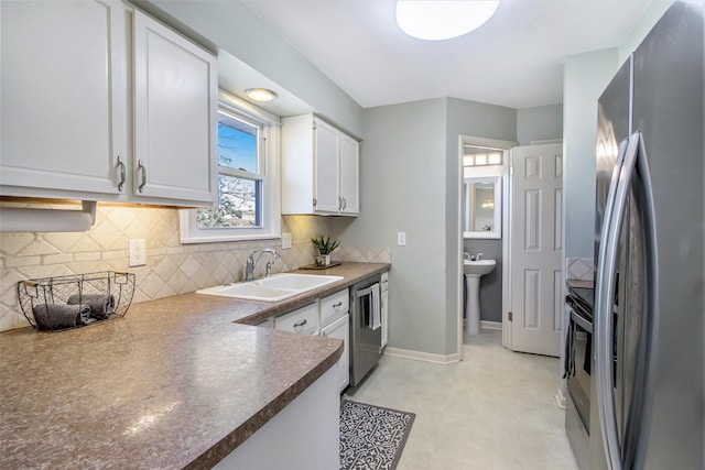 kitchen featuring a sink, tasteful backsplash, appliances with stainless steel finishes, white cabinets, and baseboards