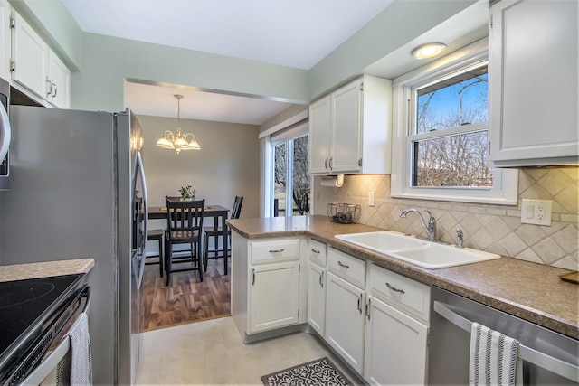 kitchen with stainless steel dishwasher, a wealth of natural light, white cabinetry, and a sink