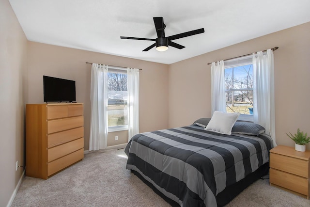 bedroom featuring multiple windows, light carpet, baseboards, and ceiling fan