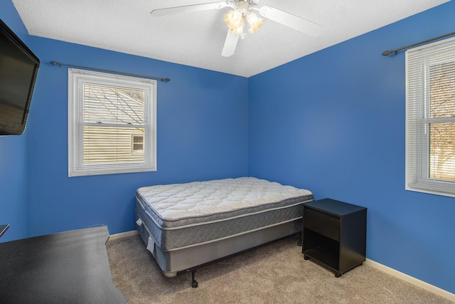 carpeted bedroom with a textured ceiling, baseboards, and ceiling fan