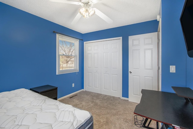 carpeted bedroom with visible vents, a ceiling fan, a textured ceiling, a closet, and baseboards