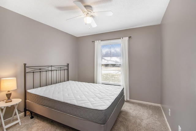 bedroom featuring baseboards, light colored carpet, ceiling fan, and a textured ceiling