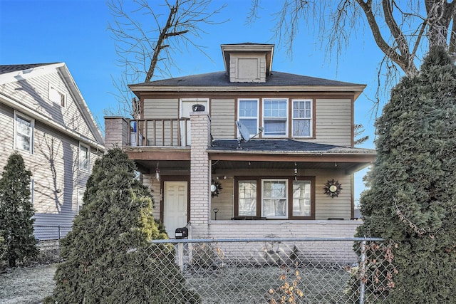 traditional style home featuring a fenced front yard, a balcony, and brick siding