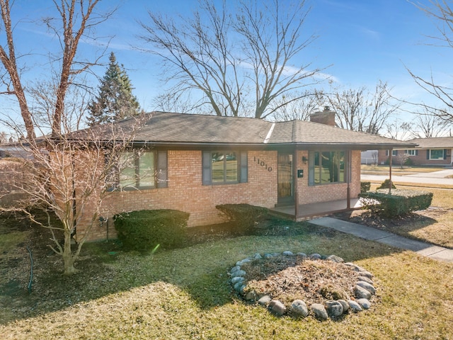 ranch-style home with brick siding, roof with shingles, and a chimney