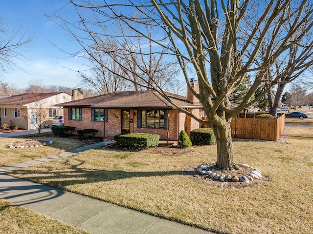 view of front of home featuring a front lawn, brick siding, a chimney, and fence