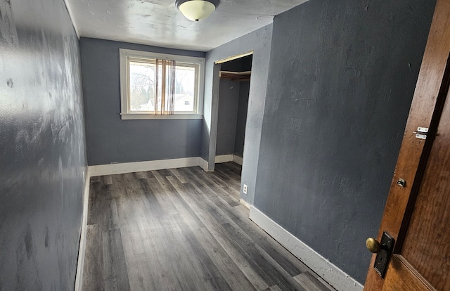 unfurnished bedroom featuring a closet, baseboards, and wood finished floors