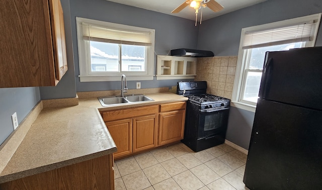 kitchen featuring ceiling fan, brown cabinets, light tile patterned flooring, black appliances, and a sink