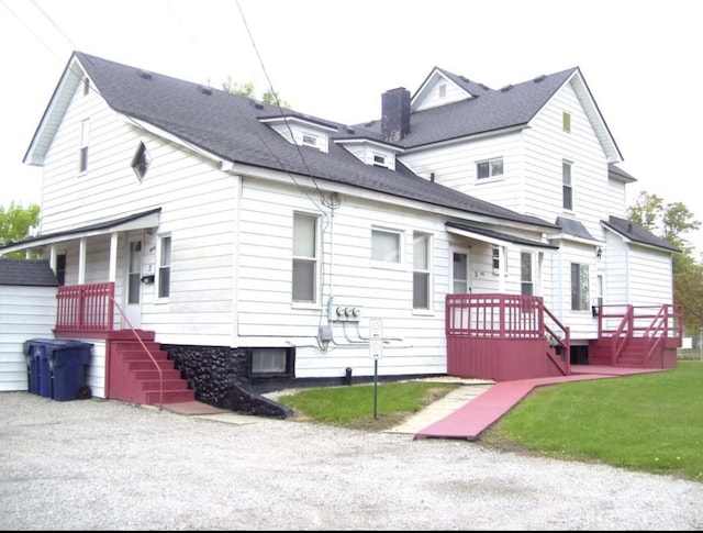 exterior space with a chimney, a front yard, and a shingled roof