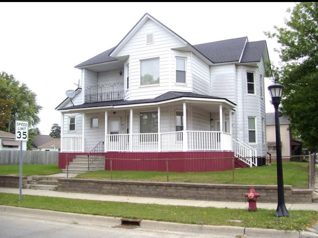 victorian house featuring a porch, a shingled roof, and fence