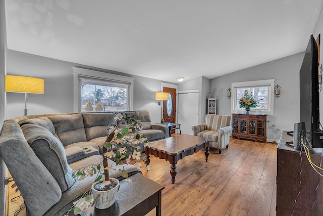 living room featuring lofted ceiling and light wood-style floors