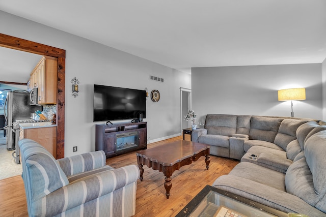 living room with visible vents, light wood-type flooring, and baseboards