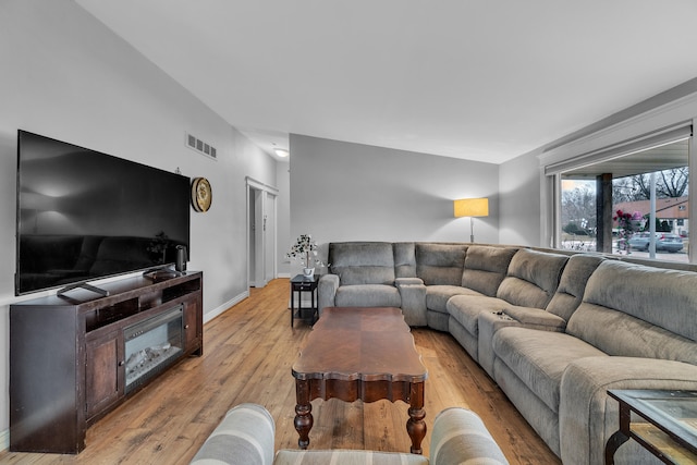 living room featuring visible vents, light wood-style flooring, and baseboards