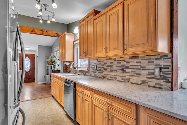 kitchen featuring backsplash, baseboards, light stone countertops, appliances with stainless steel finishes, and a sink