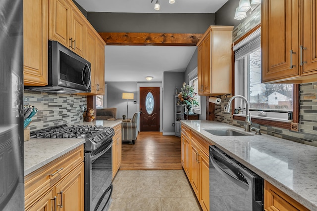 kitchen with light stone countertops, a sink, black range with gas stovetop, dishwasher, and stainless steel microwave