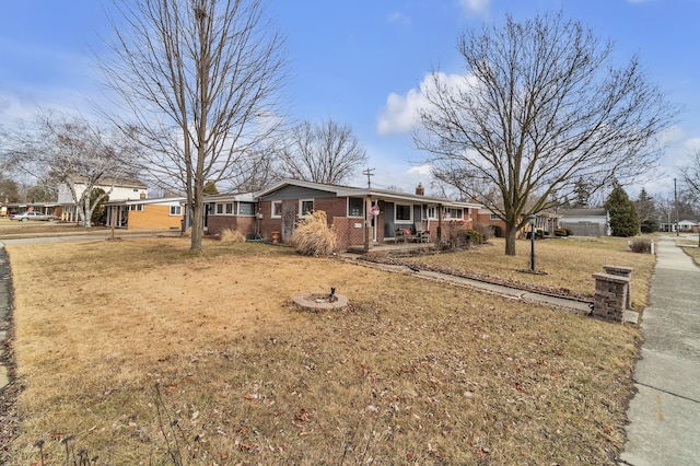 ranch-style home featuring brick siding, a chimney, and a front lawn