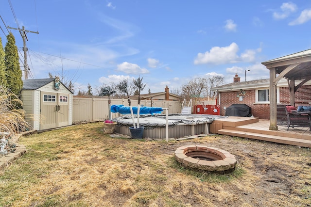 view of yard featuring a fenced backyard, a shed, a fenced in pool, and a deck