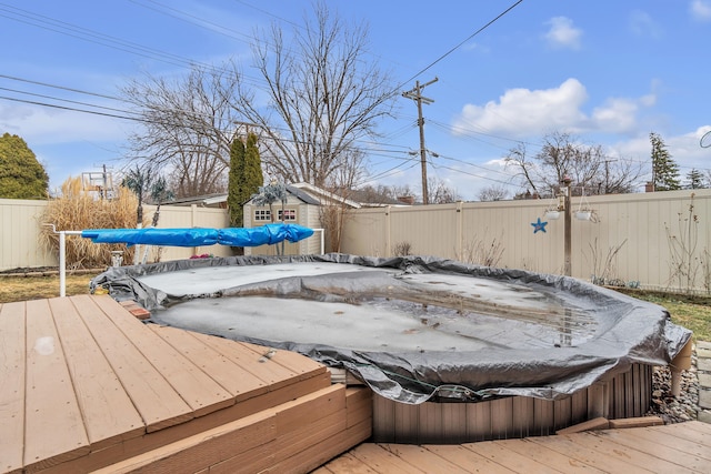 wooden terrace featuring an outbuilding, a hot tub, and a fenced backyard