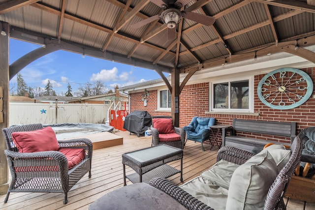 wooden terrace with area for grilling, a ceiling fan, an outdoor living space, fence, and a gazebo