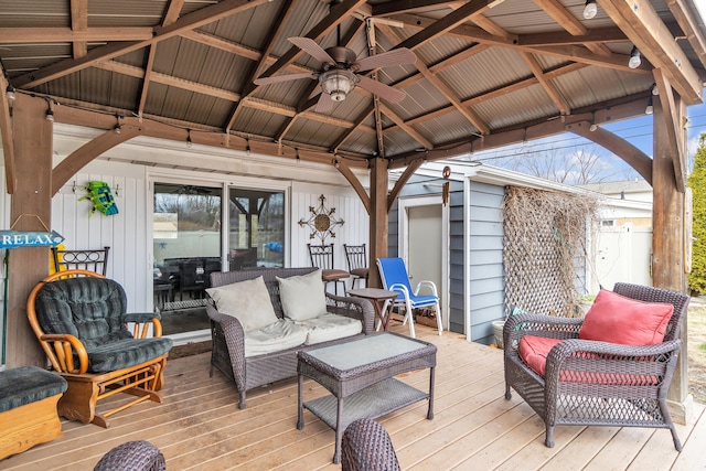 wooden deck with a gazebo, an outdoor living space, and a ceiling fan