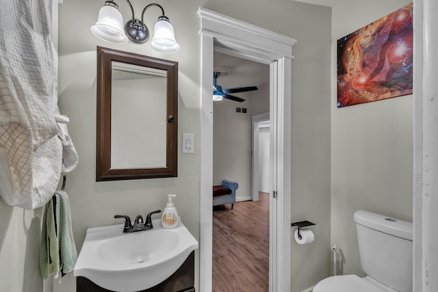 bathroom with visible vents, toilet, a ceiling fan, a sink, and wood finished floors