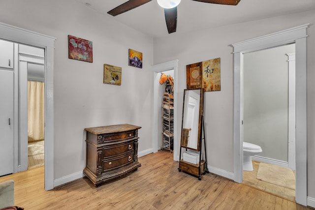 bedroom with connected bathroom, baseboards, light wood-style floors, and ceiling fan