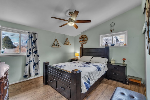 bedroom with lofted ceiling, multiple windows, baseboards, and light wood finished floors