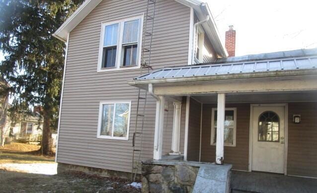 exterior space with a porch and metal roof