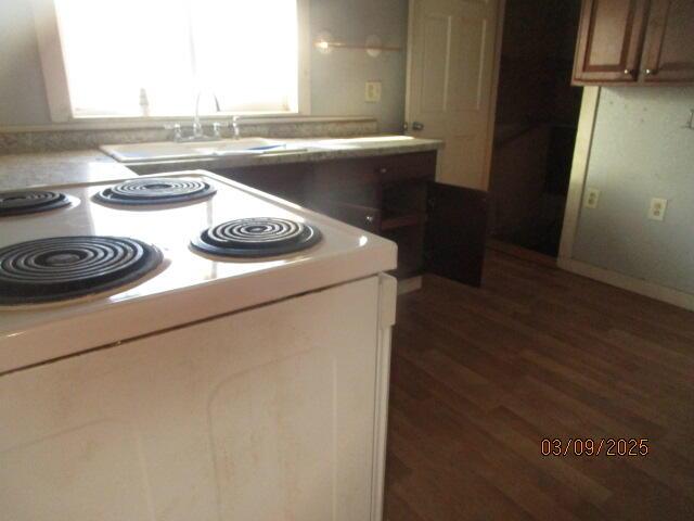 kitchen with a sink, light countertops, dark wood-style flooring, and white range with electric stovetop