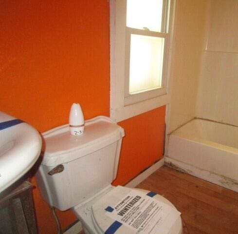 interior details featuring a bathtub, toilet, walk in shower, and wood finished floors