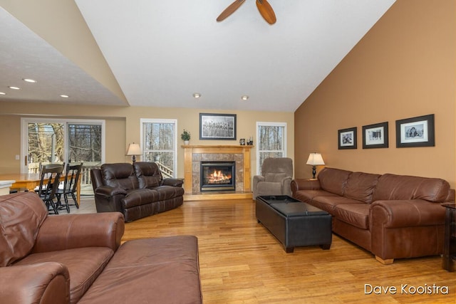 living room with a ceiling fan, high vaulted ceiling, recessed lighting, a fireplace, and light wood-type flooring