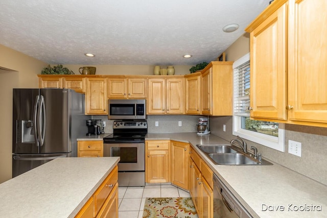 kitchen featuring light countertops, light tile patterned floors, appliances with stainless steel finishes, a textured ceiling, and a sink