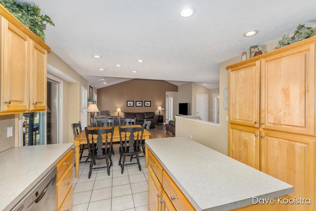 kitchen featuring a kitchen island, dishwasher, vaulted ceiling, and light countertops