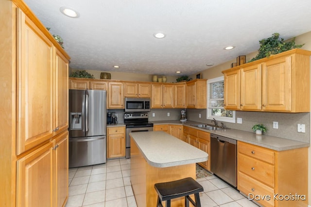 kitchen with a center island, light countertops, light tile patterned floors, stainless steel appliances, and a sink