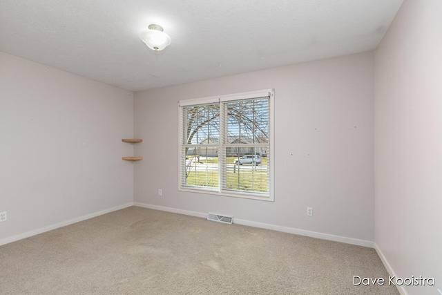 empty room featuring visible vents, baseboards, and light carpet