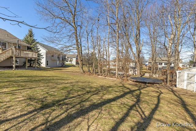 view of yard featuring a deck, stairway, and a trampoline