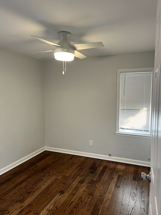 spare room with baseboards, ceiling fan, and dark wood-style flooring