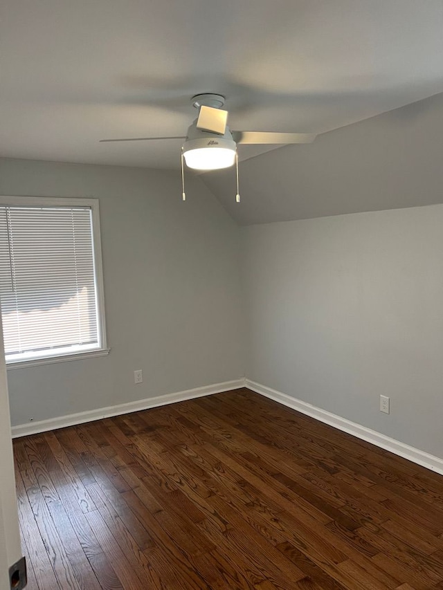 unfurnished room featuring a ceiling fan, lofted ceiling, baseboards, and dark wood-style flooring